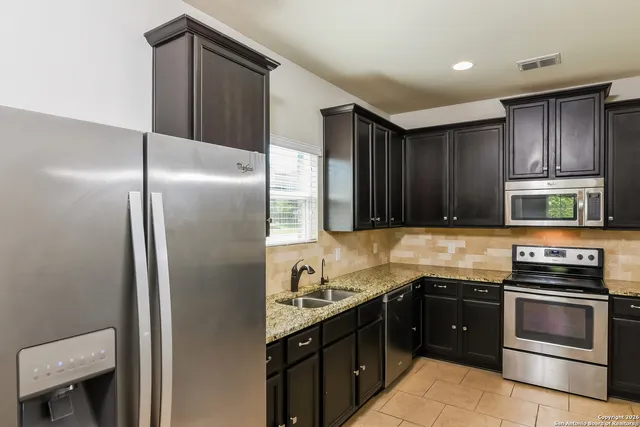 a kitchen with a refrigerator sink and cabinets