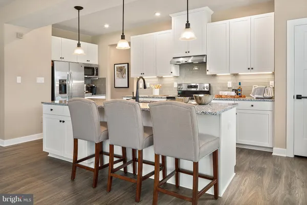 a kitchen with stainless steel appliances granite countertop a kitchen island a stove a table and chairs
