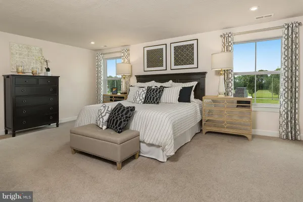 a spacious bedroom with a bed a couch and dresser