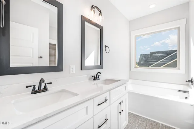 a bathroom with double vanity sink and a bathtub