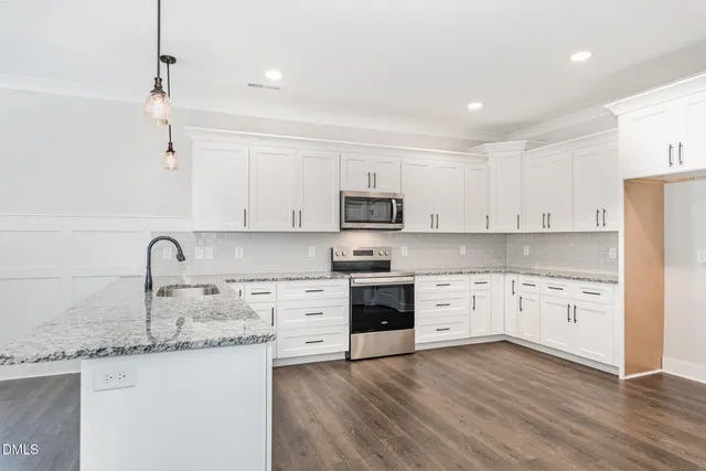 a kitchen with granite countertop a sink stainless steel appliances and white cabinets
