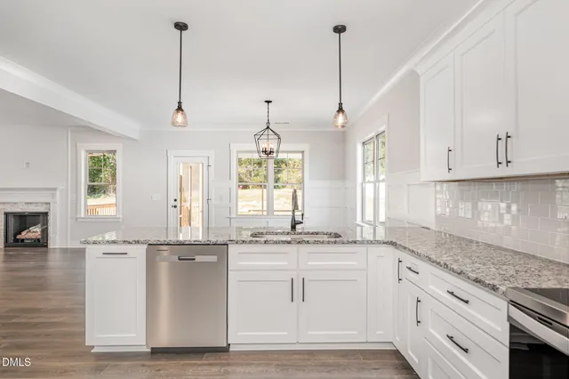 a kitchen with stainless steel appliances granite countertop a sink a window and white cabinets