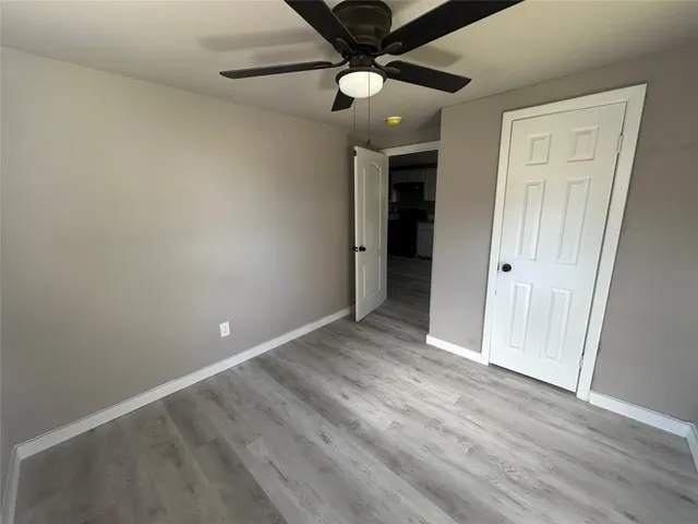 an empty room with wooden floor fan and windows
