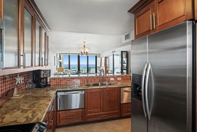 a kitchen with stainless steel appliances granite countertop a refrigerator a stove and a sink with wooden floor