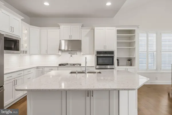 a kitchen with kitchen island granite countertop a stove top oven a sink a counter space and cabinets