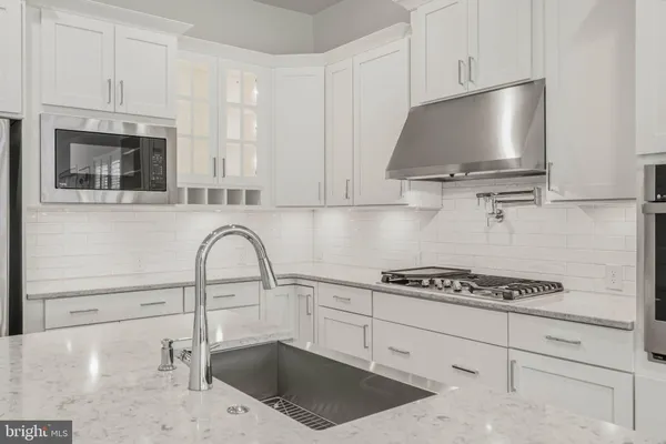 a kitchen with granite countertop a sink a stove and cabinets