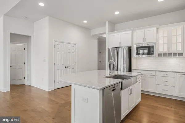 a kitchen that has a lot of white cabinets and stainless steel appliances
