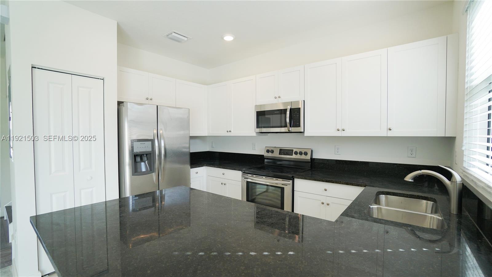 11214 Southwest 249th Street Homestead, FL 33032 - Photo 3 of 16 a kitchen with granite countertop a refrigerator and a sink