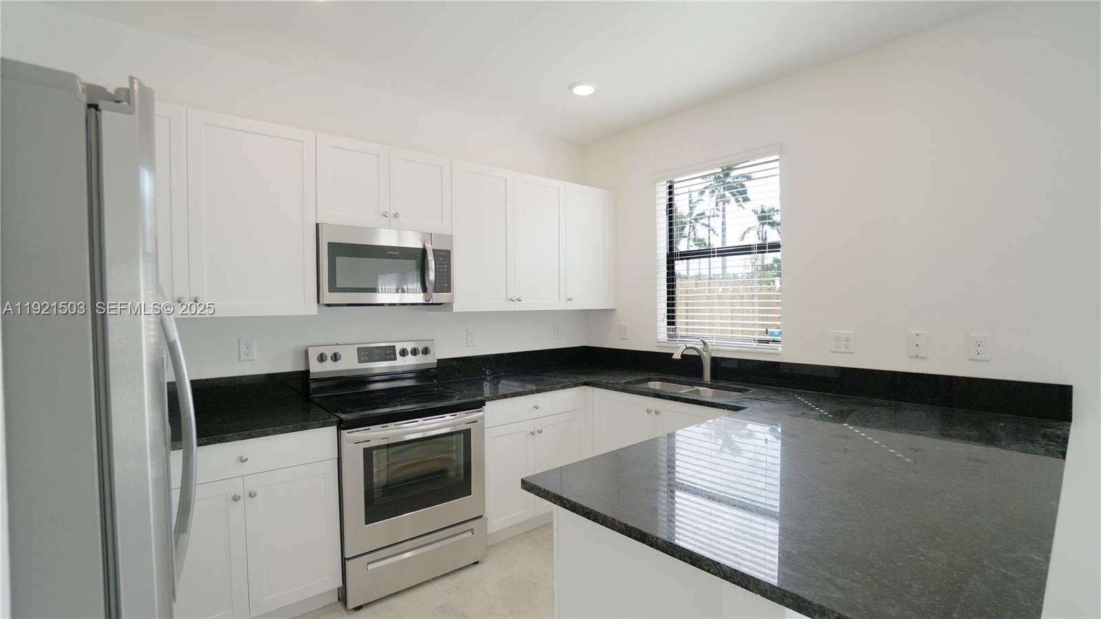 11214 Southwest 249th Street Homestead, FL 33032 - Photo 4 of 16 a kitchen with granite countertop white cabinets and black appliances