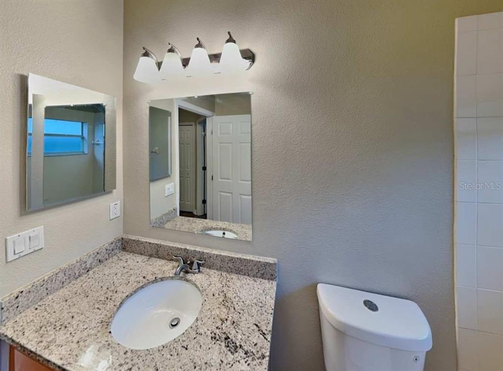 1805 Concord Drive Apopka, FL 32703 - Photo 11 of 12 a bathroom with a granite countertop sink a mirror and a toilet