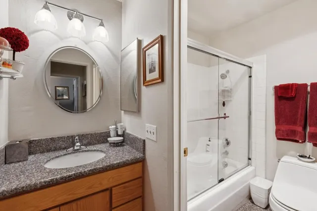 a bathroom with a granite countertop sink mirror vanity and toilet