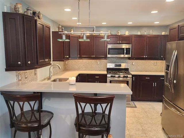 a kitchen with stainless steel appliances kitchen island granite countertop a sink a stove a microwave a dining table and chairs