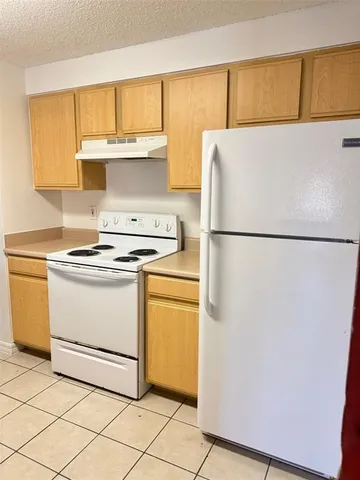a white refrigerator freezer and a stove sitting inside of a kitchen