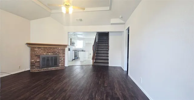 an empty room with wooden floor fireplace and windows