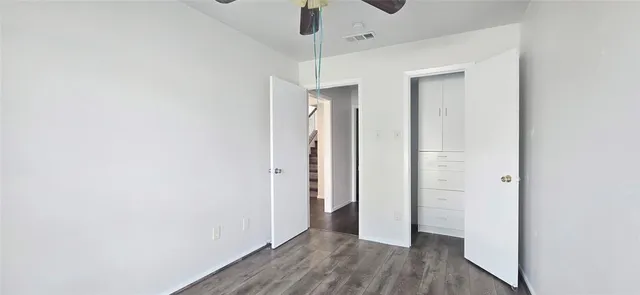 an empty room with wooden floor and a ceiling fan