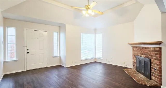 an empty room with wooden floor a ceiling fan and a fireplace