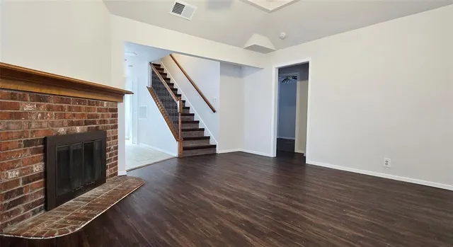 a view of an empty room with wooden floor fireplace and a window