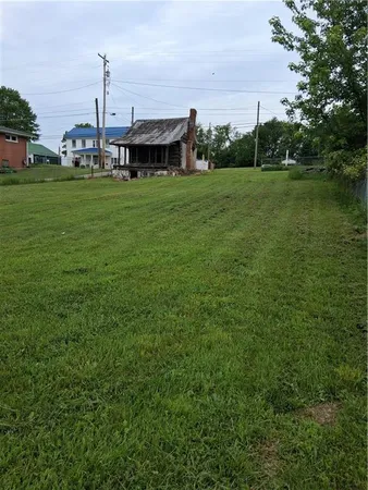 a view of a big house with a big yard and large trees