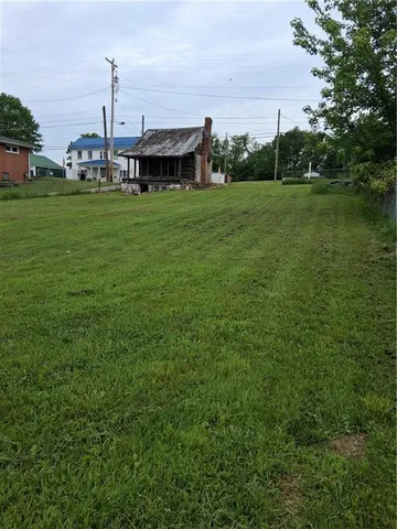 a view of a big house with a big yard and large trees