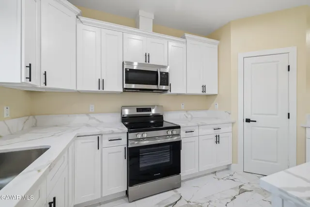 a kitchen with granite countertop a stove top oven microwave and cabinets