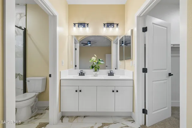 a bathroom with a granite countertop sink a toilet and a mirror