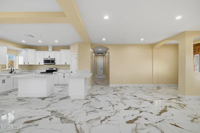 a large kitchen with stainless steel appliances kitchen island a sink a window and a refrigerator