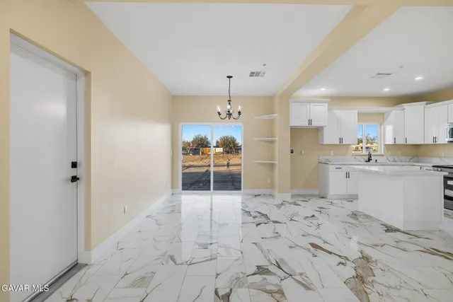 a large white kitchen with kitchen island a sink stainless steel appliances and cabinets