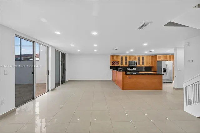 a view of kitchen with stainless steel appliances kitchen island granite countertop a refrigerator and a sink