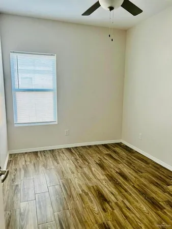 an empty room with wooden floor cabinet and windows