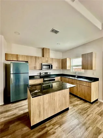 a kitchen with stainless steel appliances a refrigerator a stove a sink and white cabinets