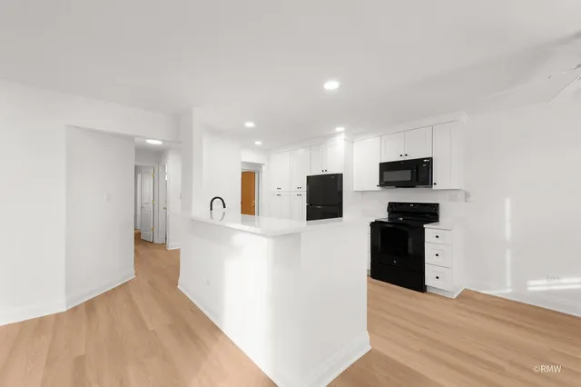 a view of kitchen with stainless steel appliances kitchen island refrigerator stove and wooden floor