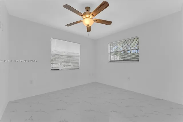 an empty room with windows and fan