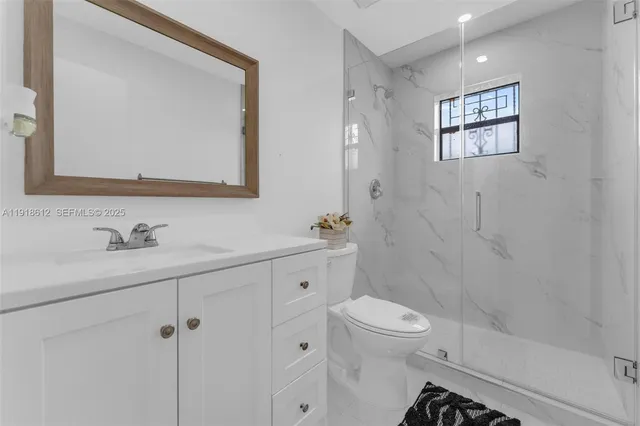 a bathroom with a toilet a sink a mirror a shower and vanity