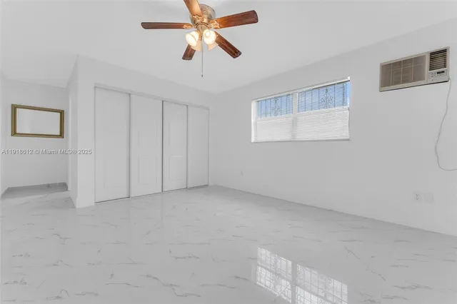 an empty room with windows and fan