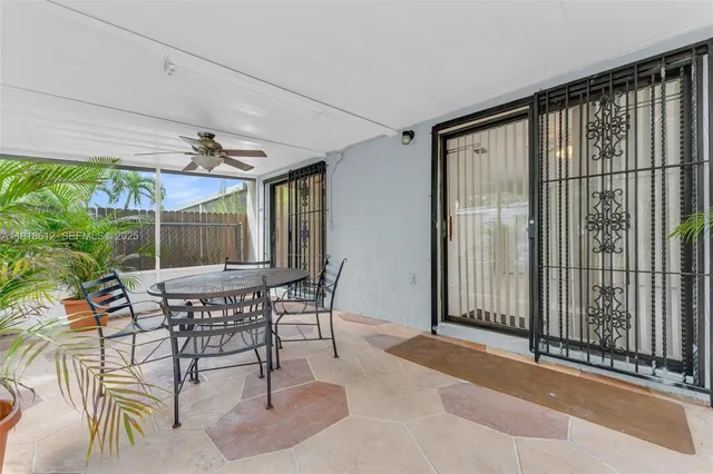 a patio with table and chairs and potted plants