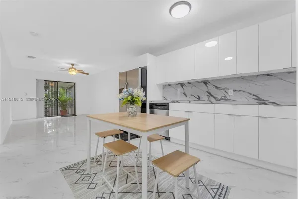 a kitchen with stainless steel appliances kitchen island granite countertop a sink a stove a dining table and chairs with wooden floor