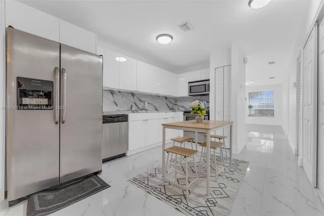 a kitchen with a refrigerator and table chairs