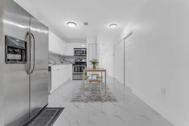 a kitchen with kitchen island a counter top space stainless steel appliances and cabinets