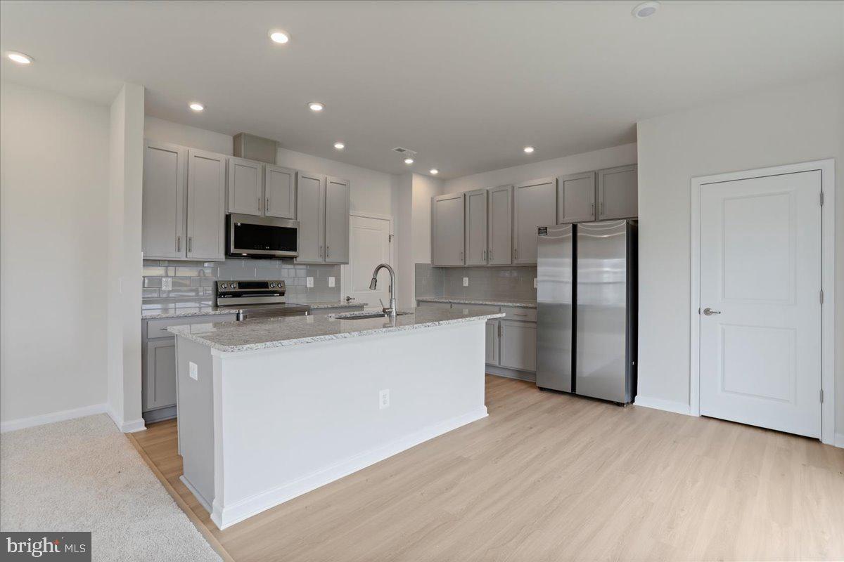 62 Peters Avenue Ranson, WV 25438 - Photo 4 of 31 a kitchen with stainless steel appliances granite countertop a refrigerator a sink a stove a microwave and white cabinets