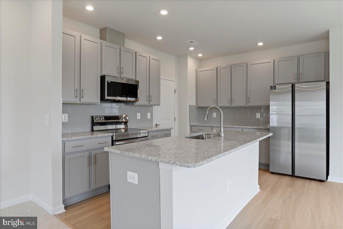 62 Peters Avenue Ranson, WV 25438 - Photo 7 of 31 a kitchen with stainless steel appliances granite countertop a refrigerator a stove a sink a microwave and white cabinets with wooden floor