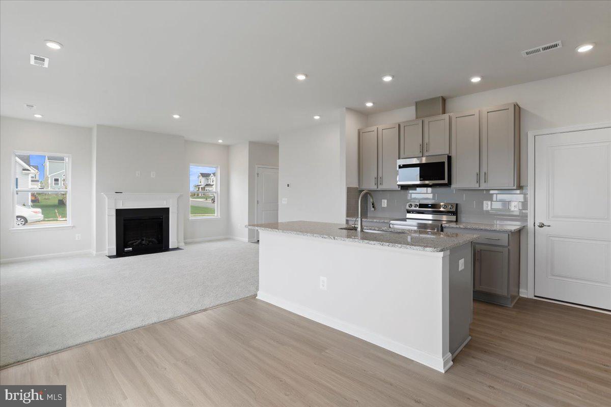 62 Peters Avenue Ranson, WV 25438 - Photo 8 of 31 a kitchen with stainless steel appliances a microwave a sink a stove a microwave a center island and a window