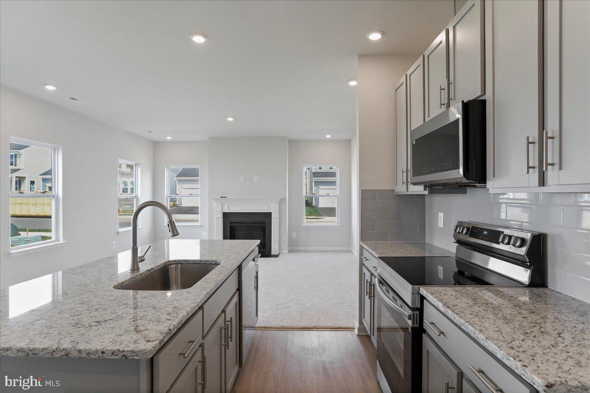 62 Peters Avenue Ranson, WV 25438 - Photo 9 of 31 a kitchen with granite countertop kitchen island a sink wooden cabinets and stainless steel appliances