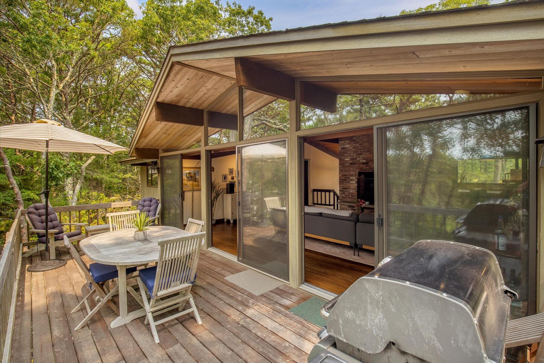 80 Woodlot Road Wellfleet, MA 02667 - Photo 14 of 67 a view of a patio with a table and chairs under an umbrella