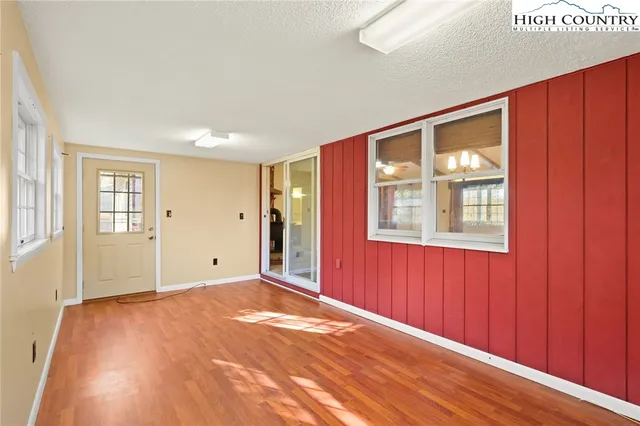 a view of an empty room with window and wooden floor