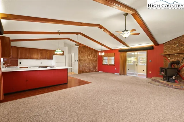 a view of an empty room with window and a kitchen