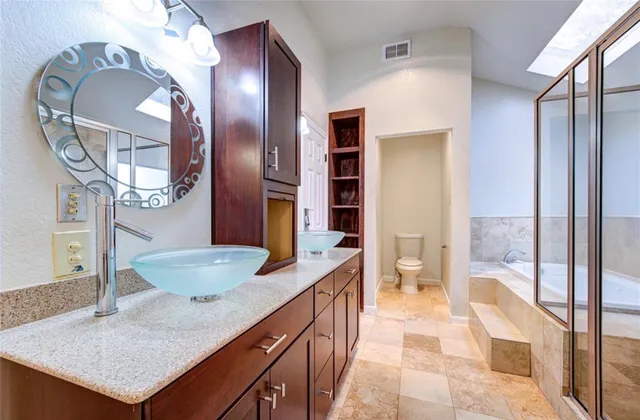 a spacious bathroom with a granite countertop sink a toilet a mirror and shower
