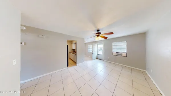 a view of an empty room with window and chandelier fan