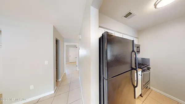 a view of a refrigerator in kitchen and an empty room