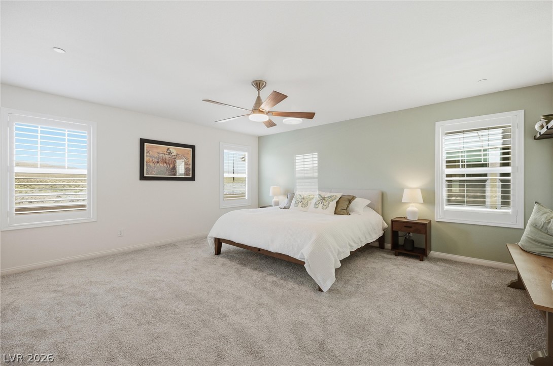 3705 Alla Rocca Avenue Henderson, NV 89044 - Photo 20 of 50 This spacious primary bedroom features soft carpeting, ample natural light, and a cooling ceiling fan.