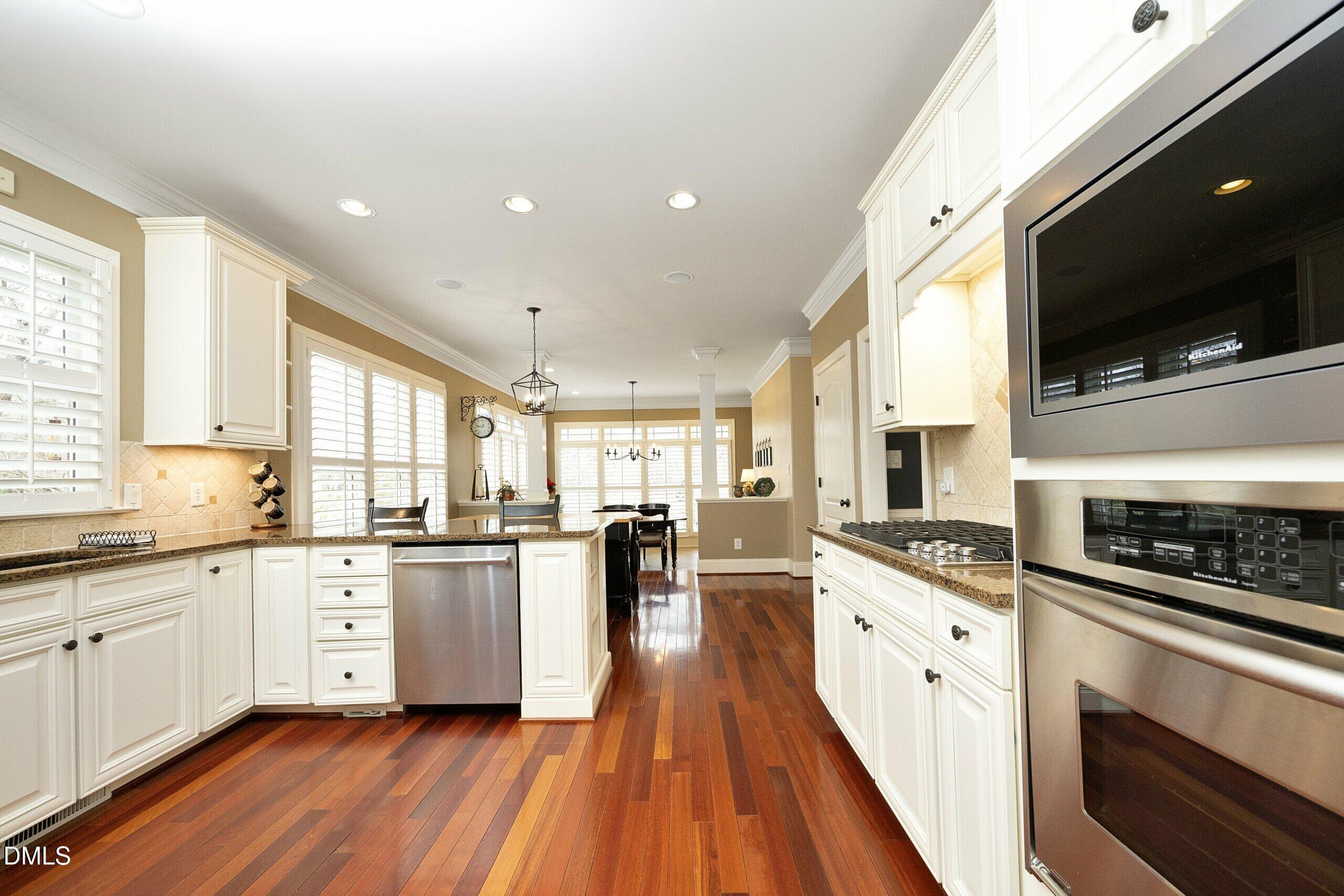 2705 Peachleaf Street Raleigh, NC 27614 - Photo 15 of 52 a large kitchen with stainless steel appliances kitchen island granite countertop a stove top oven a sink dishwasher and white cabinets with wooden floor